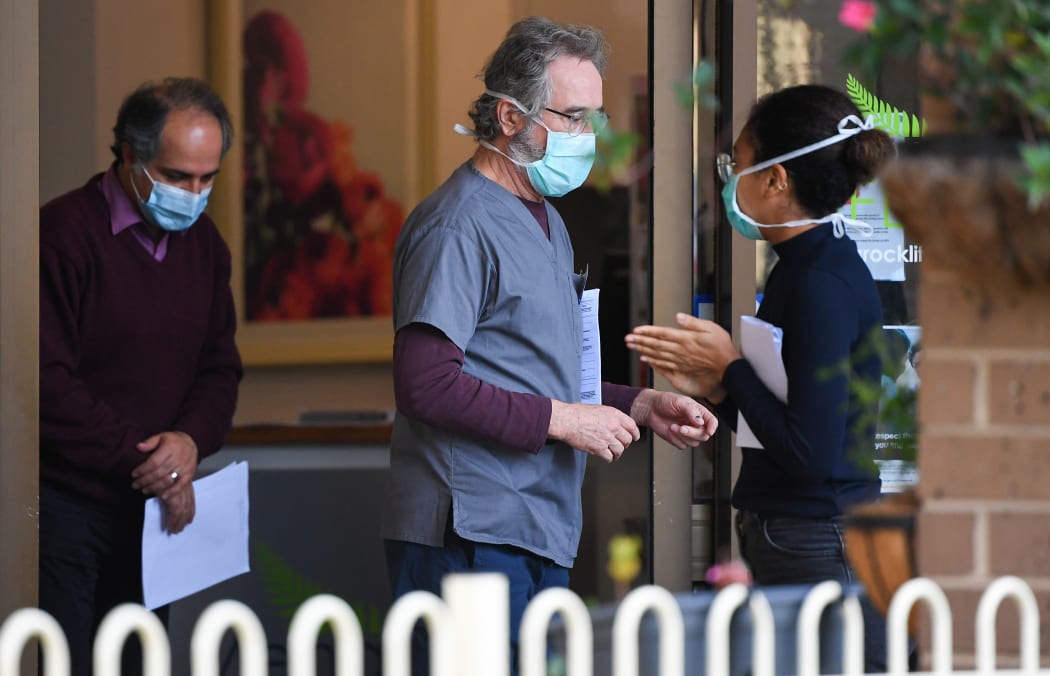 People wearing face masks are seen at the entrance of the Menarock Life aged care facility, where a cluster of infections has been reported.  There are Covid-19 cases linked to 40 aged care facilities in Victoria.