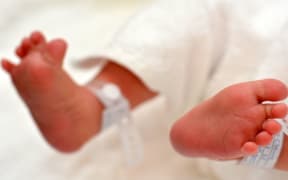 Newborn baby feet with identification bracelet tag name.