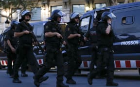 Spanish policemen walk in a cordoned off area after a van ploughed into the crowd, killing 13 persons and injuring over 80 on the Rambla in Barcelona on August 17, 2017.