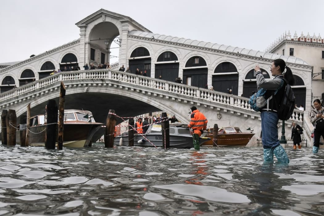 A tourist takes a photo from the flooded embankment by the Rialto bridge, after an exceptional overnight "Alta Acqua".