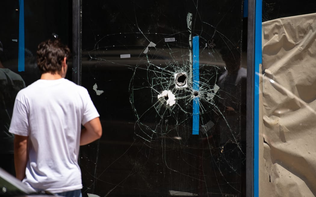 A pedestrian walks past bullet holes in the window of a store front on South Street in Philadelphia, Pennsylvania, on 5 June, 2022.