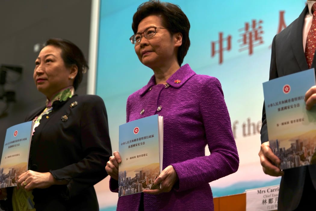Hong Kong's Chief Executive Carrie Lam (C) poses with Justice Secretary Teresa Cheng (L) while holding copies of the new national security law during a press conference at the government headquarters in Hong Kong on July 1, 2020, on the 23rd anniversary of the city's handover from Britain to China.