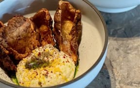 A bowl of tarama dip garnished with fried Jerusalem artichoke skins.