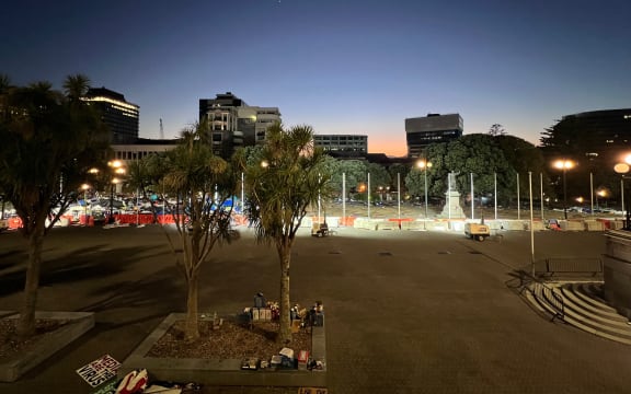 The sky going from orange to blue, above Parliament's front lawn littered with piles of broken tents.