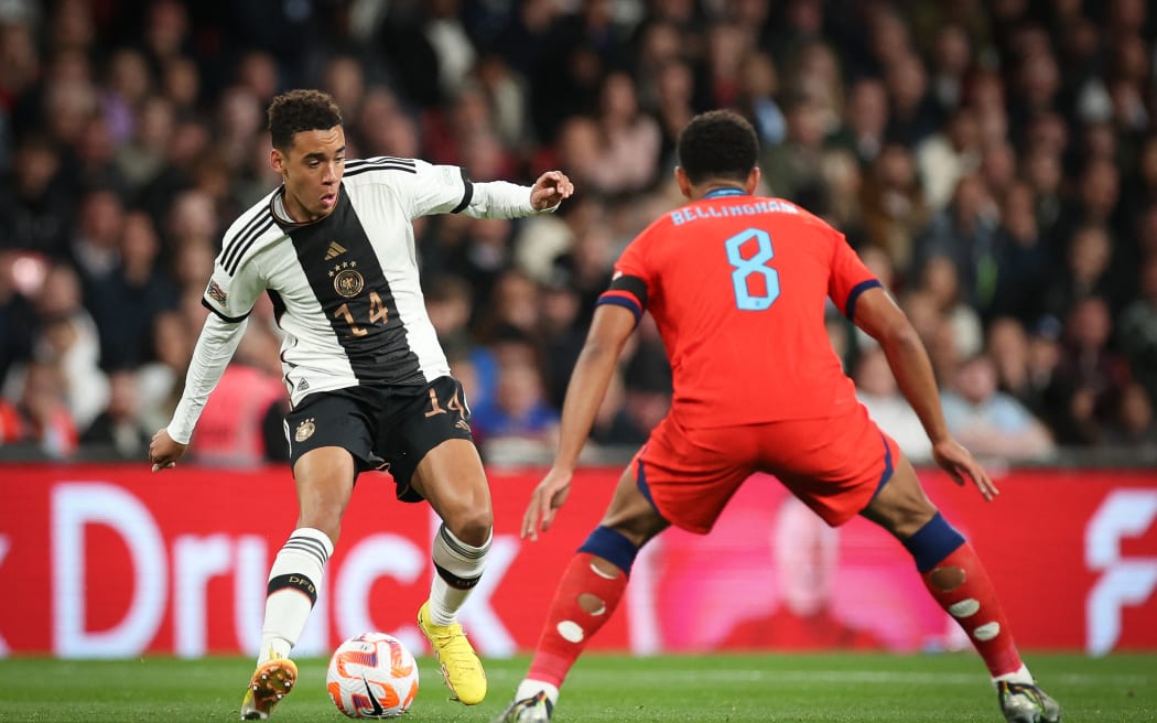 Germany's Jamal Musiala (l) and England's Jude Bellingham fight for the ball.