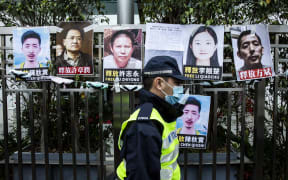 A police officer walks past placards of detained rights activists taped on the fence of the Chinese liaison office in Hong Kong on February 19, 2020, in protest against Beijing’s detention of prominent anti-corruption activist Xu Zhiyong. - Police in China have arrested Xu Zhiyong, a prominent anti-corruption activist who had been criticising President Xi Jinping’s handling of the COVID-19 coronavirus. (Photo by ISAAC LAWRENCE / AFP)