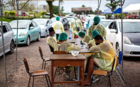 Health workers wait for residents for their dose of AstraZeneca vaccine outside a vaccination center in Suva, after Fiji announced plans to make the coronavirus vaccine compulsory for all workers as it battles a runaway outbreak of the Delta variant.