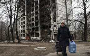 A woman  walks past a destroyed building after Russian shelling in Sviatoshinsky district of Kyiv, Ukraine on 30 March 2022.