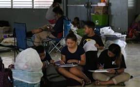 Young students do school work to pass the time while seeking shelter Monday at Astumbo Elementary School.