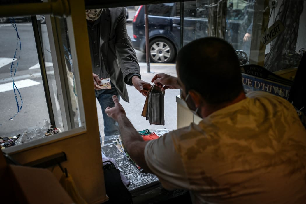 A customer buys a washable protective face mask from a tailor shop on April 28, 2020 in Paris, on the 43rd day of the Covid-19 lockdown in France.