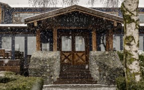 A lodge with snow falling in front of it.