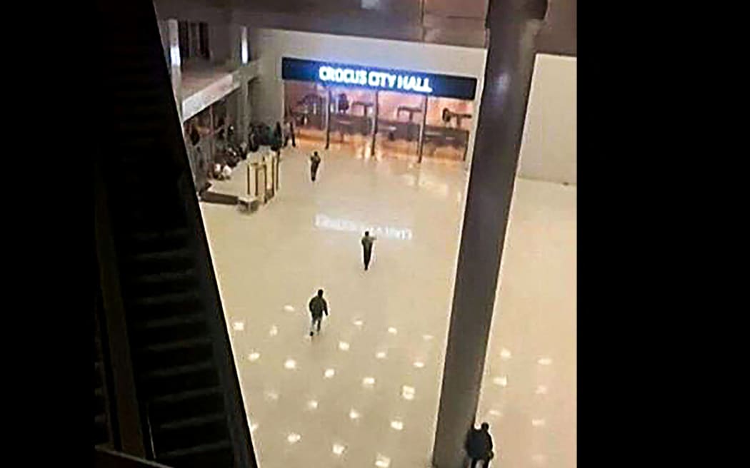 This image grab taken from footage obtained by AFP TV shows unidentified gunmen moving towards the doors of the Crocus City Hall in Krasnogorsk, outside Moscow, late on March 22, 2024. Camouflaged assailants opened fire at the packed Crocus City Hall in Moscow's northern suburb of Krasnogorsk on March 22, 2024, evening ahead of a concert by Soviet-era rock band Piknik in the deadliest attack in Russia for at least a decade. Russia on March 23, 2024, said it had arrested 11 people -- including four gunmen -- over the attack on a Moscow concert hall claimed by Islamic State, as the death toll rose to over 100 people. (Photo by -UGC / UGC / AFP) / RESTRICTED TO EDITORIAL USE - MANDATORY CREDIT "AFP PHOTO / UGC - NO MARKETING NO ADVERTISING CAMPAIGNS - DISTRIBUTED AS A SERVICE TO CLIENTS - NO ARCHIVE
