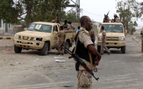 Armed Yemeni men stand next to the entrance of an army headquarters near Aden airport after Yemeni government forces supported by a Saudi-led coalition recaptured it from suspected jihadists following an hours-long firefight on July 6, 2016 in the southern city.