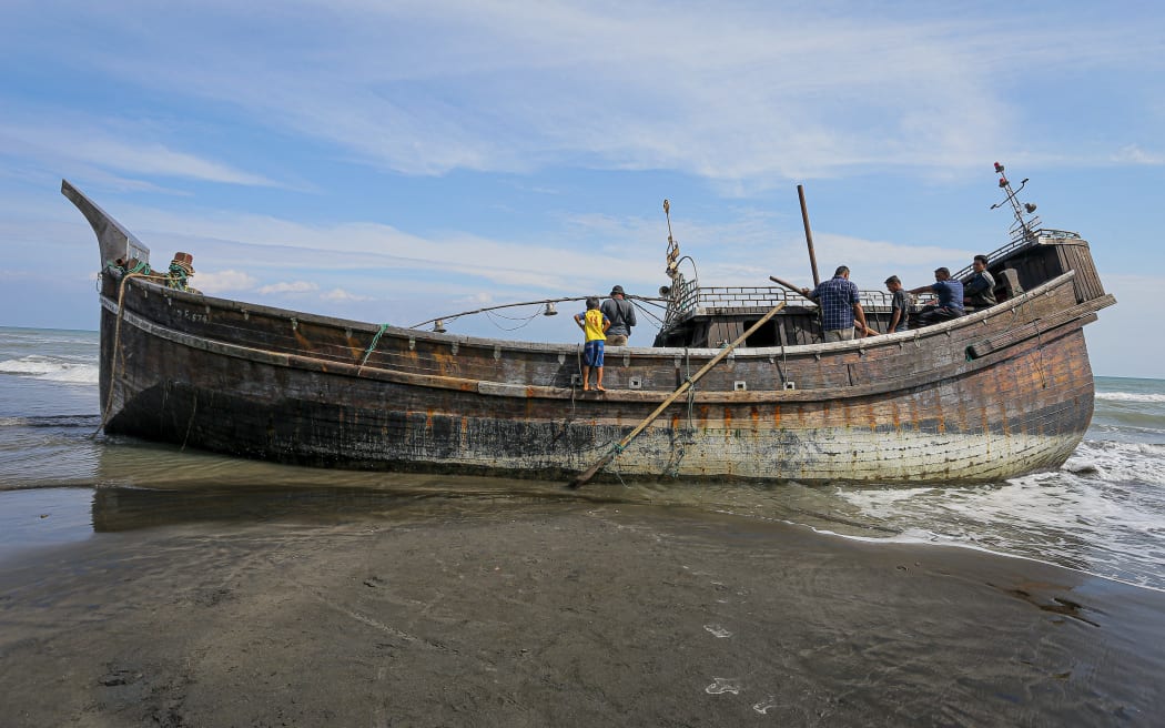 Villagers look at a wooden boat used by Rohingya people in Pidie, Aceh province on December 27, 2022. - Rohingya refugees received emergency medical treatment after a boat carrying nearly 200 people came ashore in Indonesia on December 26, authorities said, in the fourth such landing in the country in recent months. (Photo by AMANDA JUFRIAN / AFP)