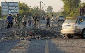 People look at a damaged bridge after Thailand carried out air strikes in an area between Cambodia's Oddar Meanchey and Siem Reap provinces on 20 December, 2025.