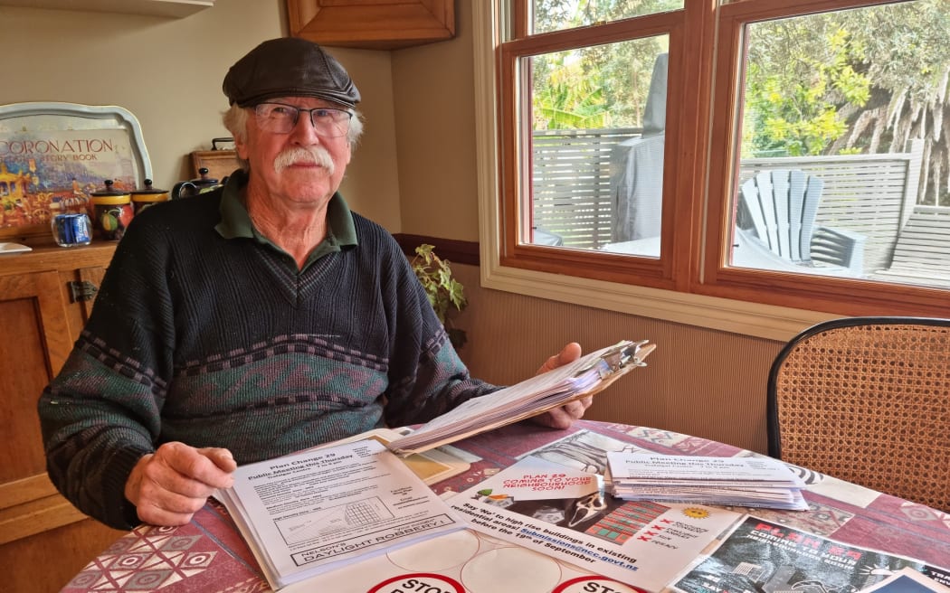 Tim Bayley sits at a table with some of the flyers he has printed out.