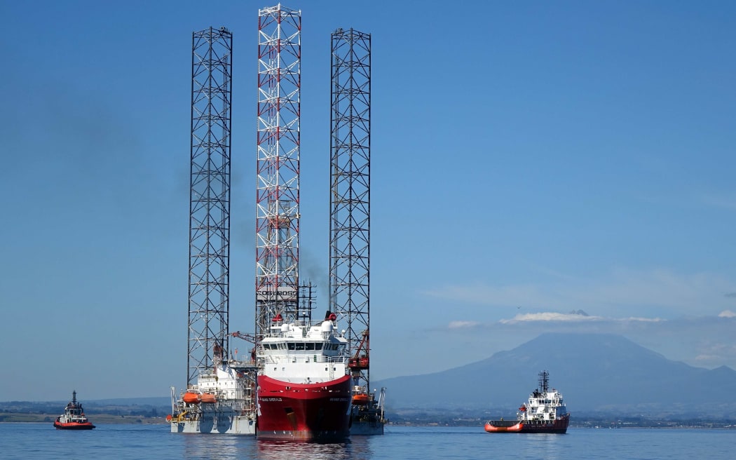 Boat and oil rig in clam sea and mountain behind