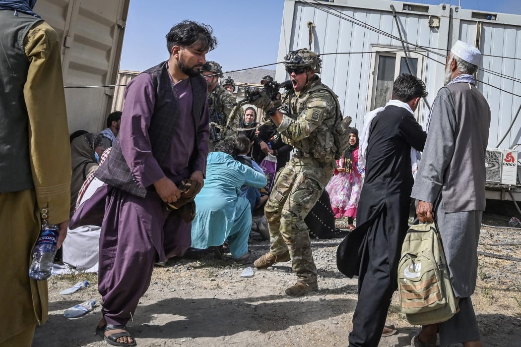 A US soldier point his gun towards an Afghan passenger at the Kabul airport on 16  August 2021, as thousands rushed to the airport after the Taliban seized power.