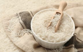 Raw basmati rice, bowl, scoop and cloth, closeup