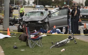 Emergency officials stand over the car that was involved after a suspected drunk driver crashed into a crowd of spectators during the Oklahoma State University homecoming parade.