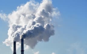 Industrial smoke from a chimney against blue sky