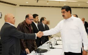Venezuela's President Nicolas Maduro (R) shaking hands with Venezuelan opposition spokesman Jesus Torrealba, before a meeting between Venezuela's government and opposition leaders in a bid to settle the country's deepening political crisis