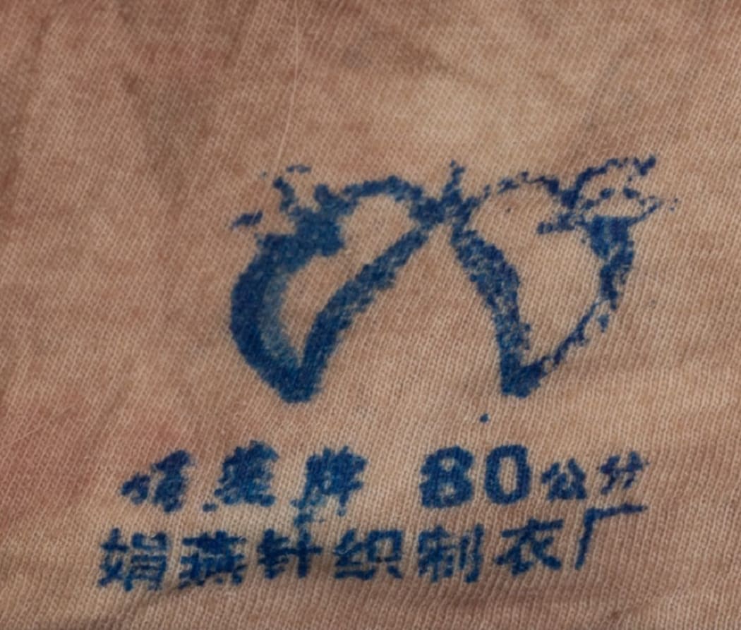 A brand's emblem on a light-coloured singlet found on the body of a woman found dead in Gulf Harbour on 12 March, 2024.