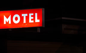 A worn motel sign lit up at night in Otahuhu