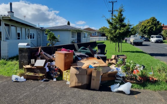 Flood-damaged furniture and  household items are piled on the roadside on a Mt Roskill street.