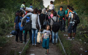 Migrants walk down a railroad towards Hungary near the northern Serbian town of Horgos.