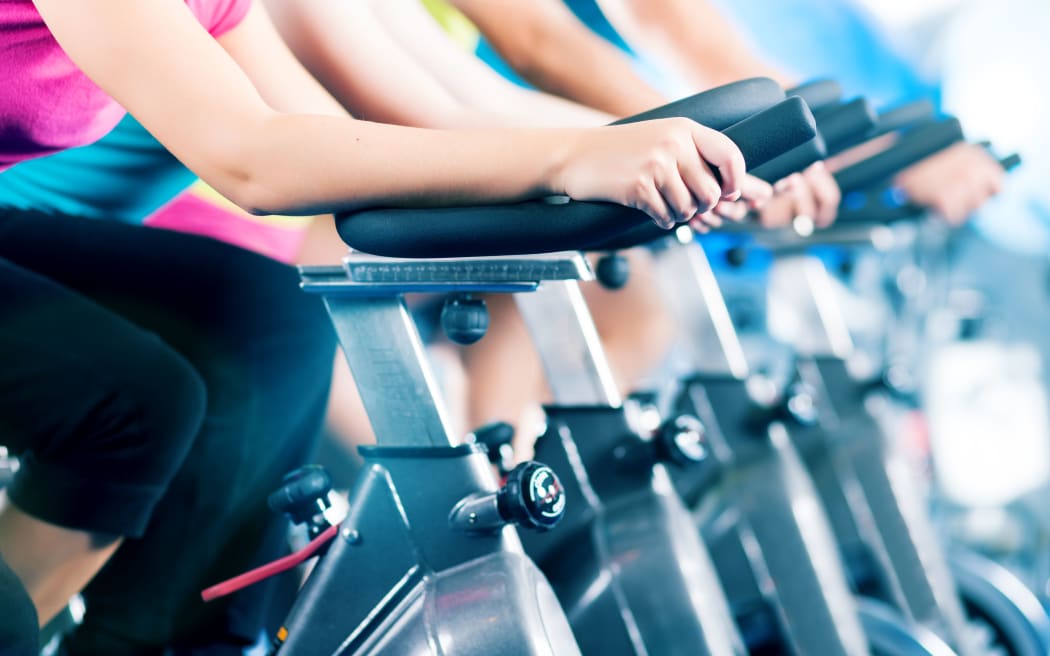 Group of four people spinning in the gym, as they take part in a HIIT class.