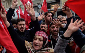 Protesters shout slogans and wave Turkish national flags in front of the Dutch Consulate in Istanbul.