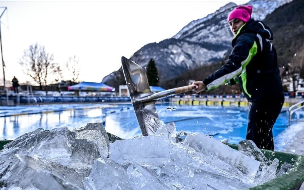 Event staff break up ice which covered the competition pool