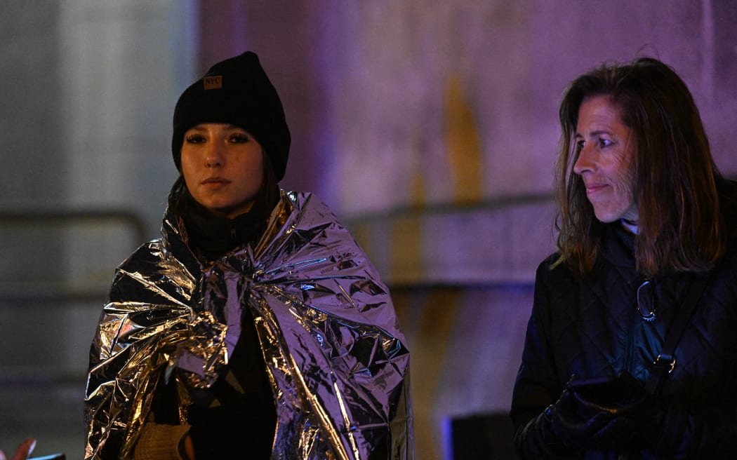 A young woman with a first aid thermal blanket looks on, in the area near the Charles University in central Prague where a gunman killed 14 people on 21 December 21, 2023.