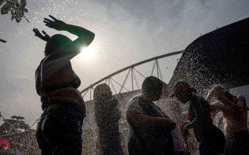 Fans of US singer Taylor Swift cool off as they queue outside the Nilton Santos Olympic Stadium before Swift's concert, "Taylor Swift: The Eras Tour", amid a heat wave in Rio de Janeiro on November 18, 2023. American superstar Taylor Swift on Saturday was mourning the death of a 23-year-old fan during her first show in Brazil before a crowd of 60,000. The death occurred as much of central and southeastern Brazil has been suffering an unusually oppressive springtime heat wave. (Photo by Tercio TEIXEIRA / AFP)