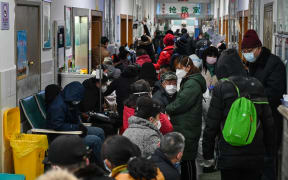 People wearing face masks wait for medical attention at Wuhan Red Cross Hospital in Wuhan on January 25, 2020.