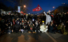 Protesters sit in front of Turkish riot police on 22 March, 2025, during a demonstration outside Istanbul's city hall to support Istanbul mayor Ekrem Imamoglu, following his arrest in connection with two probes.