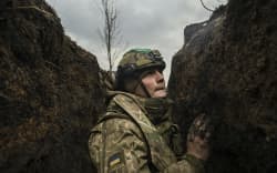 A Ukrainian serviceman takes cover in a trench during shelling next to a 105mm howitzer  near the city of Bakhmut, on March 8, 2023, amid the Russian invasion of Ukraine. (Photo by Aris Messinis / AFP)