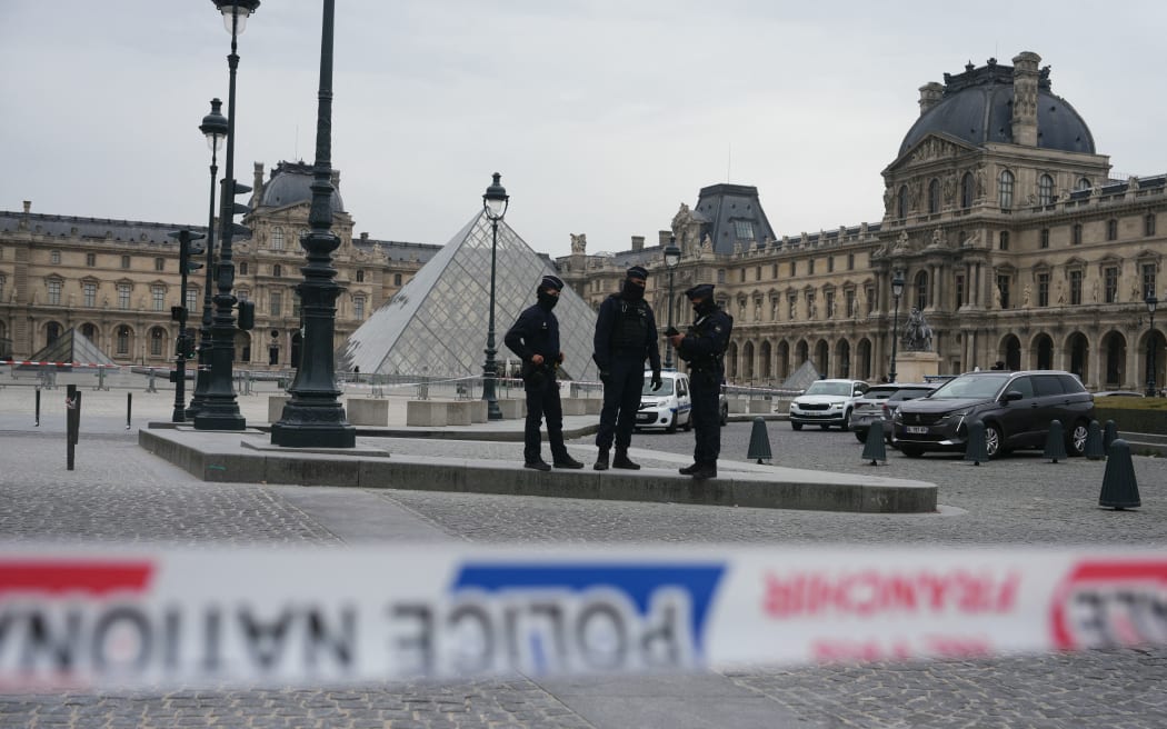 (FILES) French police officers patrol in front of the Louvre Museum after it was robbed, with the Louvre Pyramid designed by Ieoh Ming Pei in the background, in Paris on October 19, 2025. Police have arrested five new people, including a main suspect, over this month's daring jewellery theft from the Louvre museum, the Paris prosecutor said on October 30, 2025.