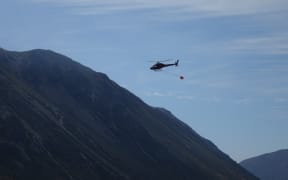 A helicopter with a monsoon bucket fights the fire near Craigieburn Forest Park.