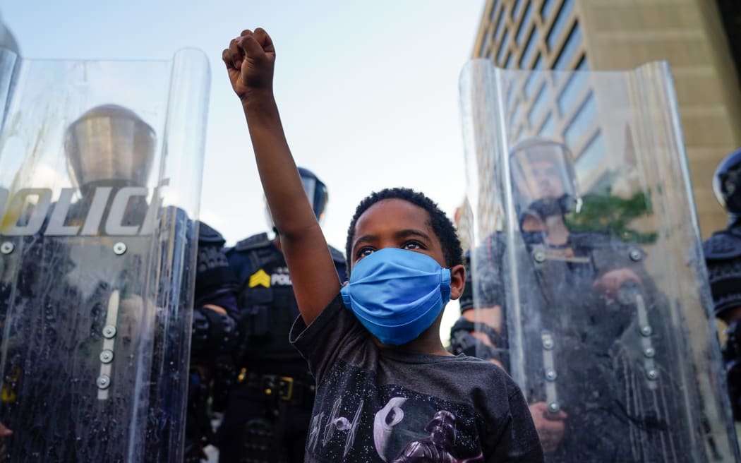A young boy raises his fist for a photo by a family friend during a demonstration on May 31, 2020 in Atlanta, Georgia.