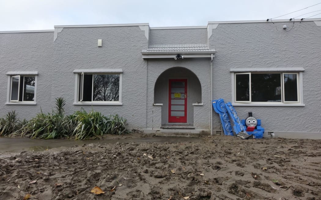 A home with a mudcaked front yard after the 2015 floods.