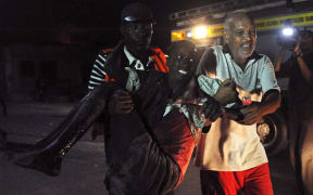 Residents help a man wounded during an attack in the center of Mogadishu on 26 February 2016.