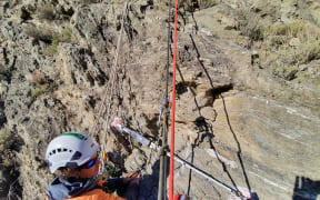 Geotech abseiler Wayo Carson at work keeping our roads safe, at Nevis Bluff, near Arrowtown.