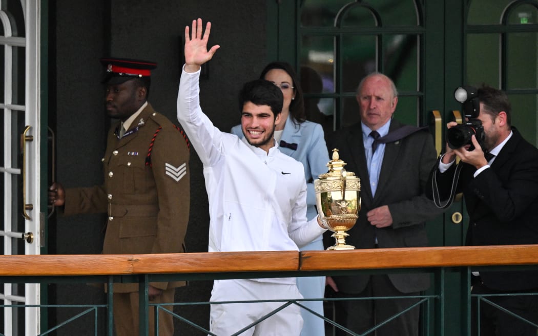 Spain's Carlos Alcaraz waves as he holds the winner's trophy on a balcony of the Centre Court building after beating Serbia's Novak Djokovic during their men's singles final tennis match on the last day of the 2023 Wimbledon Championships at The All England Tennis Club in Wimbledon, southwest London, on July 16, 2023. (Photo by Glyn KIRK / AFP) / RESTRICTED TO EDITORIAL USE