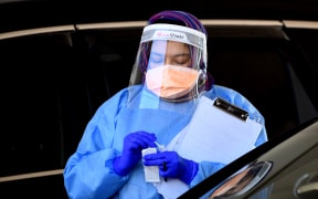 A health worker takes a swab sample at a Covid-19 drive-through testing site in western Sydney on August 7, 2021.