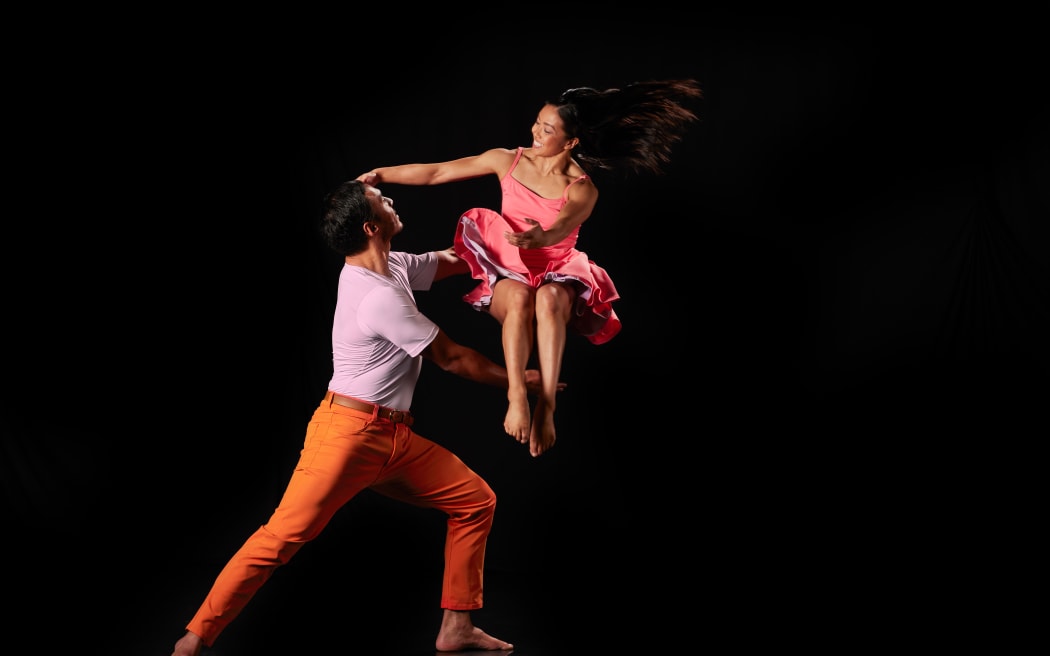 A couple dancing against a black backdrop.