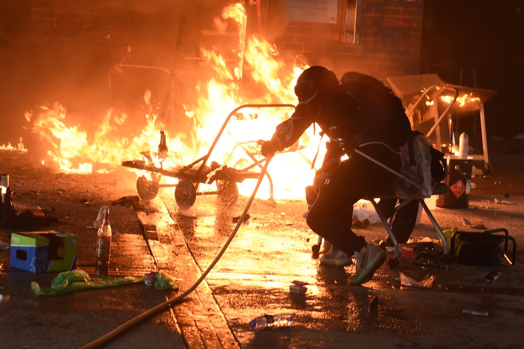 A student tries to extinguish a fire at the entrance of Hong Kong Polytechnic University.