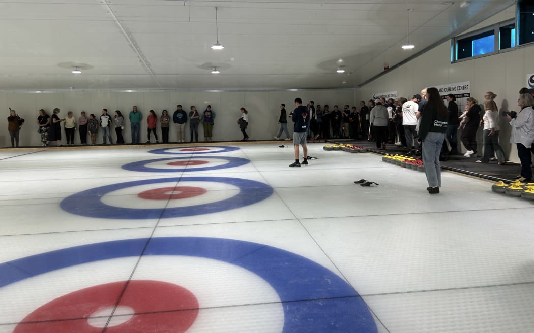 Picture shows a group of people gathered around an ice field.