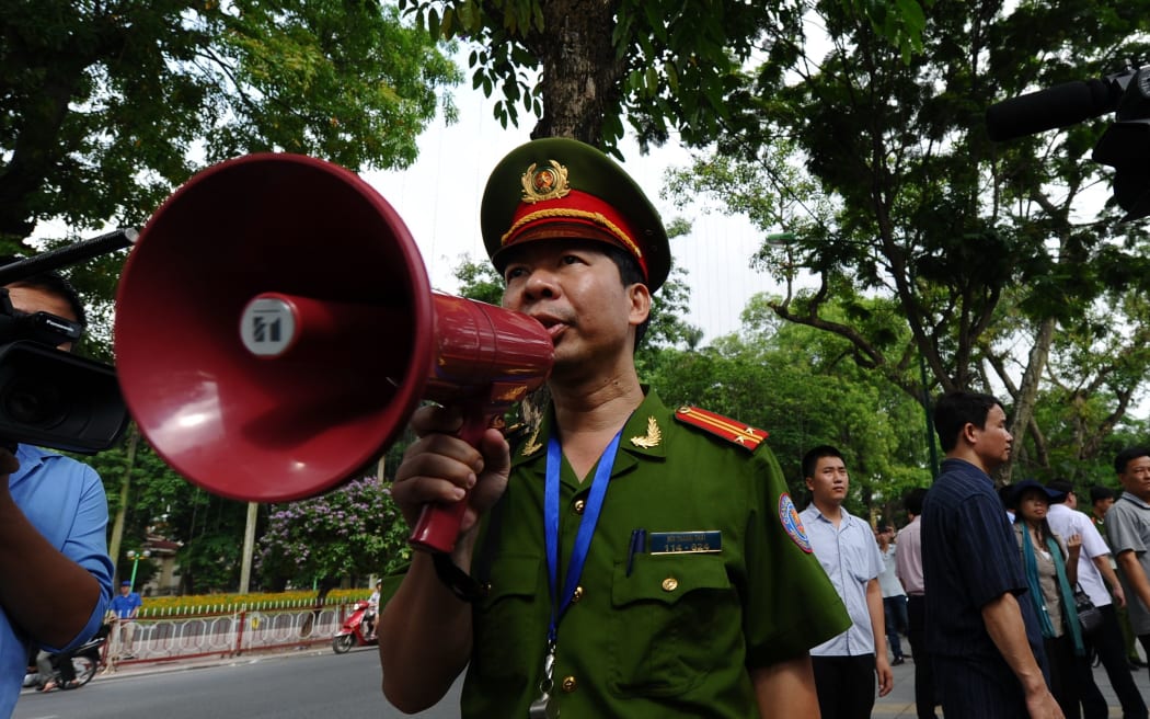 A policeman uses a megaphone to ask people not to gather on a street near the Chinese embassy in Hanoi.